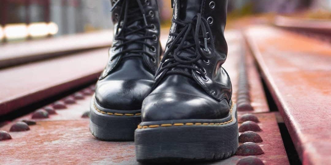 A person walking in black leather shoes. 